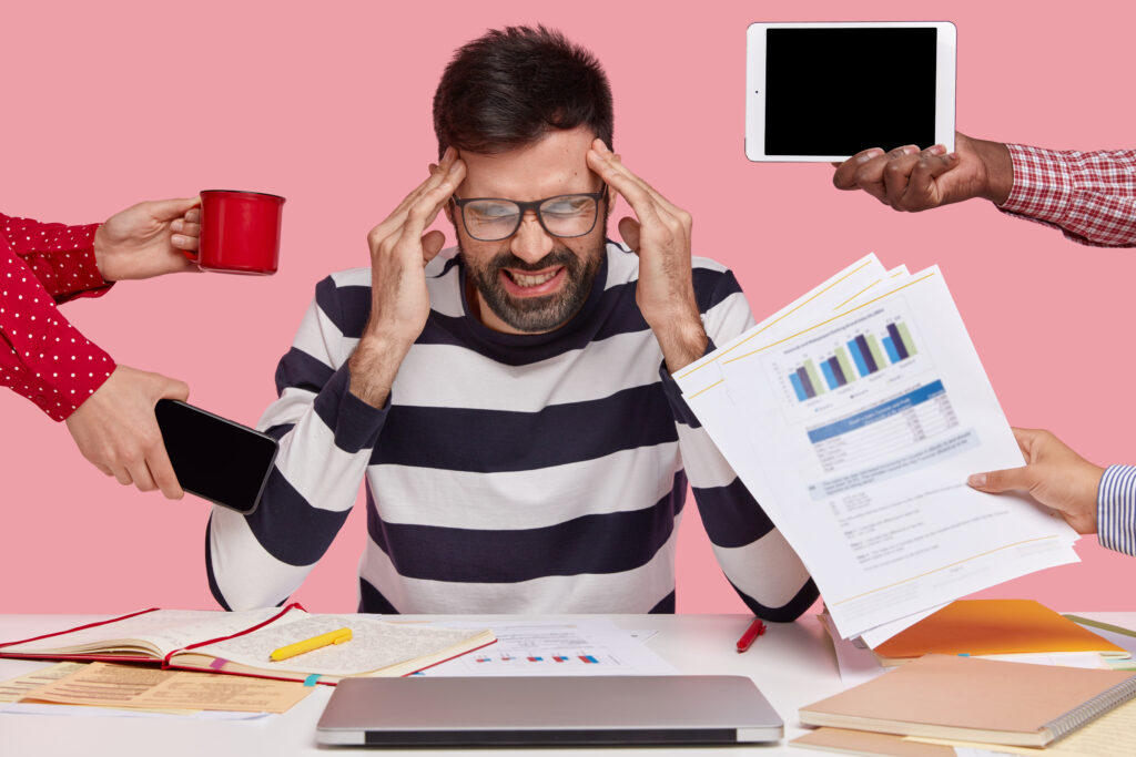 Working Professional sitting at a desk surrounded with gadgets papers