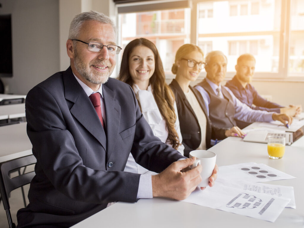 smiling senior manager with his colleagues sitting together meeting